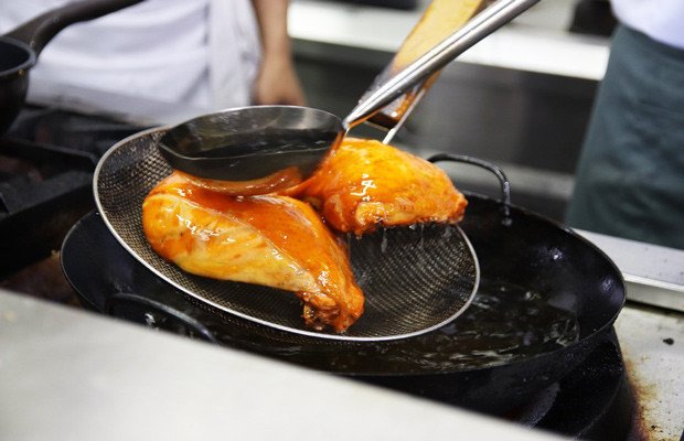 Xối dầu liên tục lên gà để tạo lớp da giòn rụm cho cơm gà xối mỡ