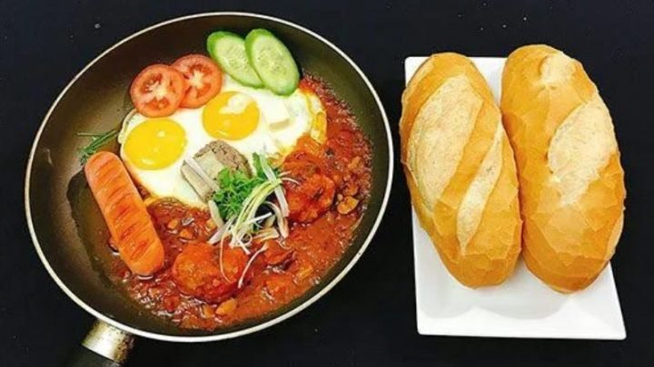 Bánh mì áp chảo với trứng ốp la và xúc xích trên chảo gang