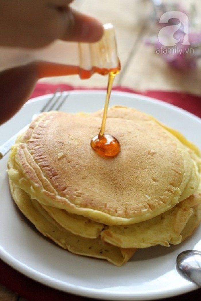 Bánh pancake bơ mật ong đã chiên xong, được rót thêm mật ong và trang trí với dâu tây