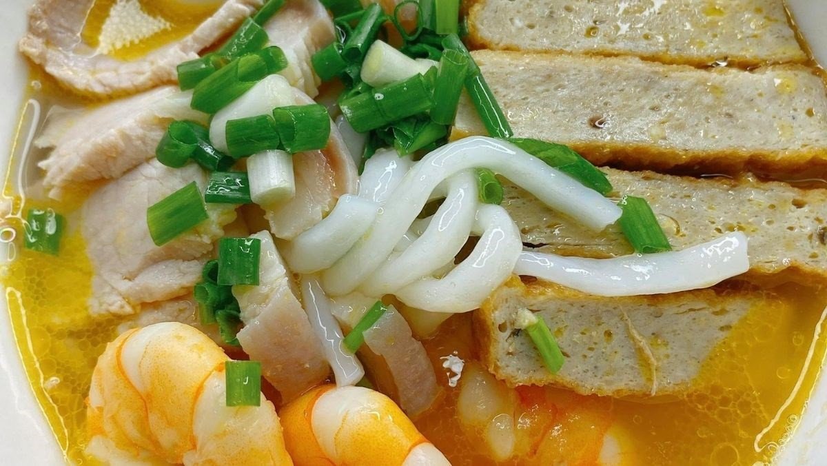 Bát bánh canh bột gạo tôm thịt nóng hổi đầy đủ tôm, thịt, chả cá, hành lá và hành phi thơm lừng trên bàn ăn gỗ, sẵn sàng thưởng thức.