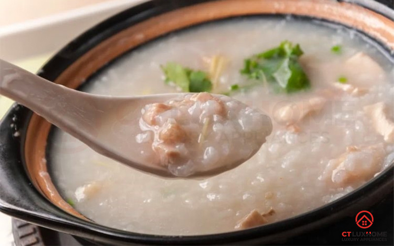 Bát cháo trắng nóng hổi được rắc thêm hành lá và gừng thái sợi, đặt cạnh một đĩa đồ ăn kèm.