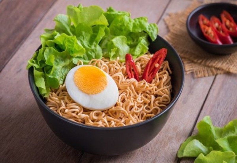 Bát mì tôm với nhiều topping như xúc xích, trứng, thịt, cho thấy việc tăng lượng calo đáng kể