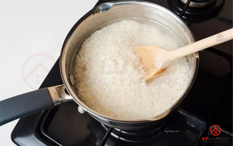 Bếp ga đang đun một nồi cháo trắng trên bếp từ màu đen.