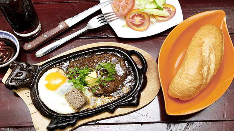 Bò bít tết phong cách Việt Nam ăn kèm trứng ốp la và pate, thể hiện lượng calo đáng kể