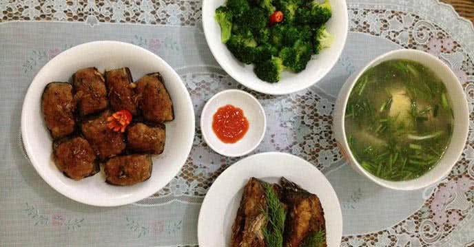 Bữa cơm với canh cá, cá chim chiên giòn, súp lơ xào và cà tím nhồi thịt