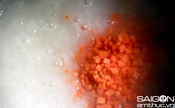 Cà rốt thái hạt lựu được thêm vào nồi cháo đang sôi, chuẩn bị cho món cháo tim dinh dưỡng