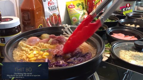 Các loại topping tươi ngon như hải sản, thịt bò và rau được thêm vào nồi mì cay Hàn Quốc đang sôi