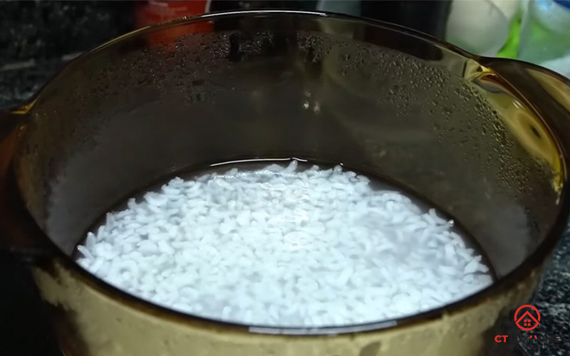 Các nguyên liệu cơ bản để nấu cháo trắng gồm gạo trong bát, một thìa muối và gừng thái lát trên thớt gỗ.