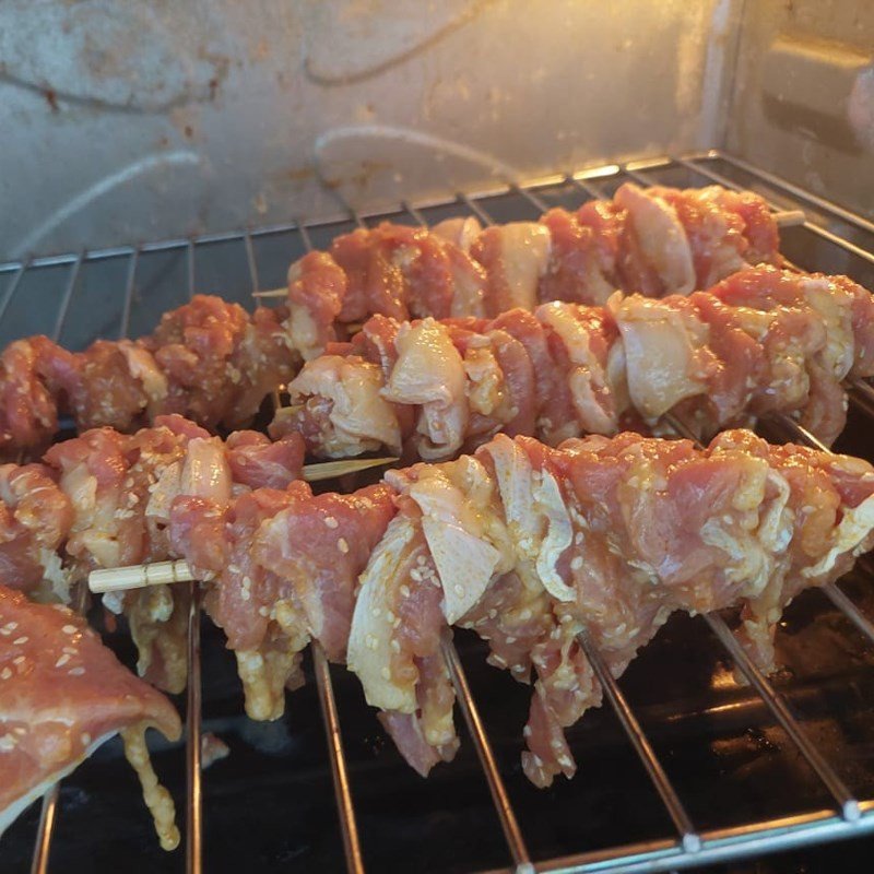 Các xiên thịt nướng đang được lật mặt trên lò, chuẩn bị quét sốt
