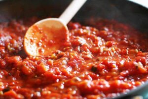 Chảo sốt cà chua thịt băm đang sôi nhẹ, chuẩn bị cho món mì Ý Bolognese đậm đà.