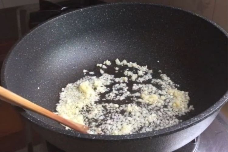 Chảo su su đang được xào trên bếp với tỏi phi thơm, giữ được màu xanh tươi mát