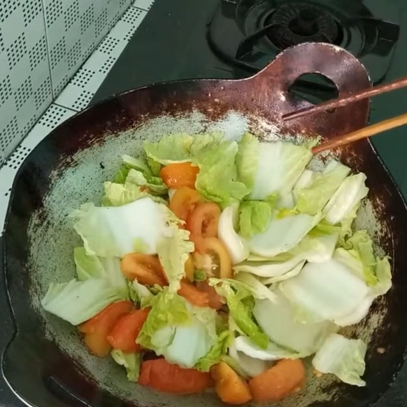 Cho cải thảo vào xào cùng cà chua, đảo đều tay
