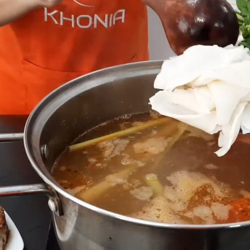 Cho măng chua và rau ngổ vào nồi lẩu thái cá bớp, chuẩn bị hoàn thành món ăn