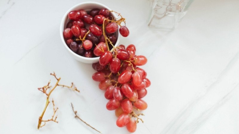 Chùm nho tím tươi ngon trên bàn, tượng trưng cho lợi ích dinh dưỡng của quả nho