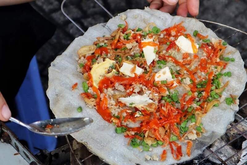 Cô gái đang thưởng thức một chiếc bánh tráng nướng, gợi ý cách ăn uống thông minh để kiểm soát calo