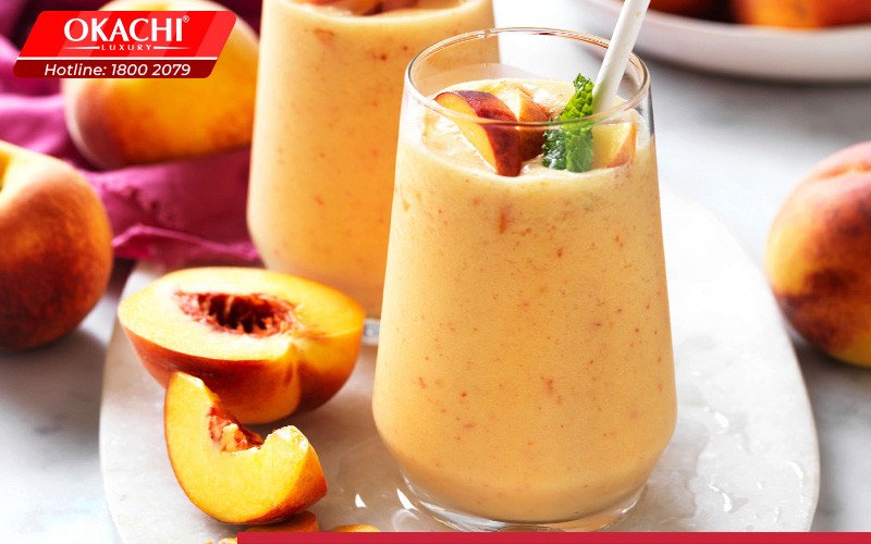 Cốc sinh tố đào mịn màng, hấp dẫn, cùng những trái đào tươi bên cạnh.