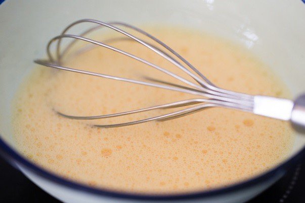 Đánh tan trứng gà để chuẩn bị làm món trứng chiên sốt cà chua