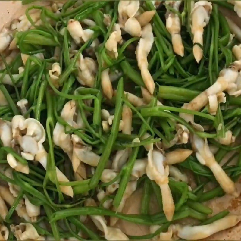 Đảo đều ốc móng tay và rau muống trên chảo nóng