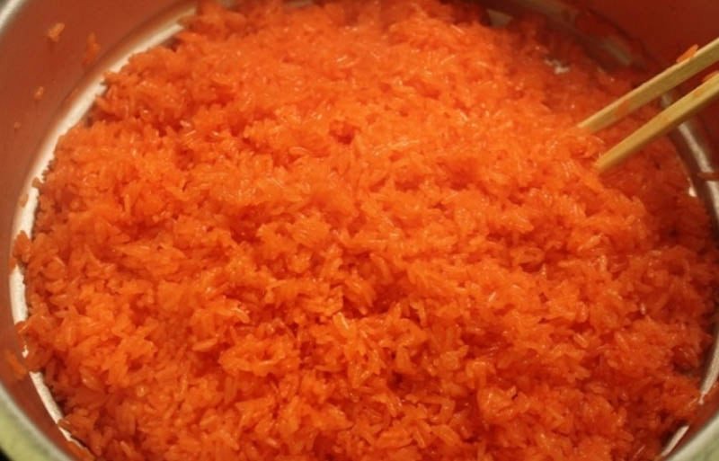 Đảo đều xôi gấc trong nồi hấp để hạt nếp chín đều