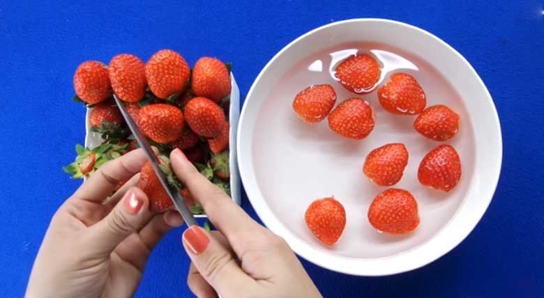 Dâu tây tươi đang được ngâm trong nước muối loãng để làm sạch