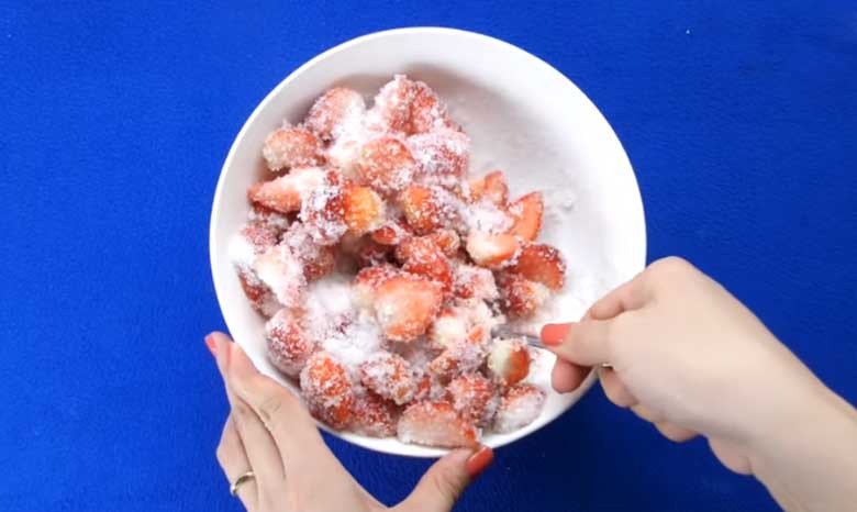 Dâu tây tươi đang được ướp với đường cát trắng trong tô lớn