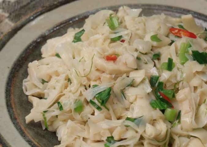 Đĩa măng đắng xào tỏi thơm ngon sau khi chế biến, rắc thêm chút tiêu và rau mùi.