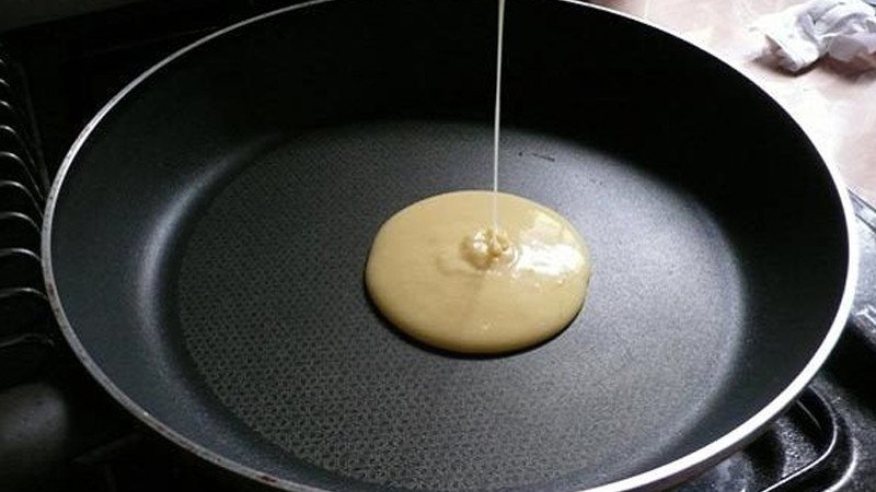 Đổ bột làm bánh rán Doremon đơn giản từ bột mì vào giữa chảo để tạo hình tròn.