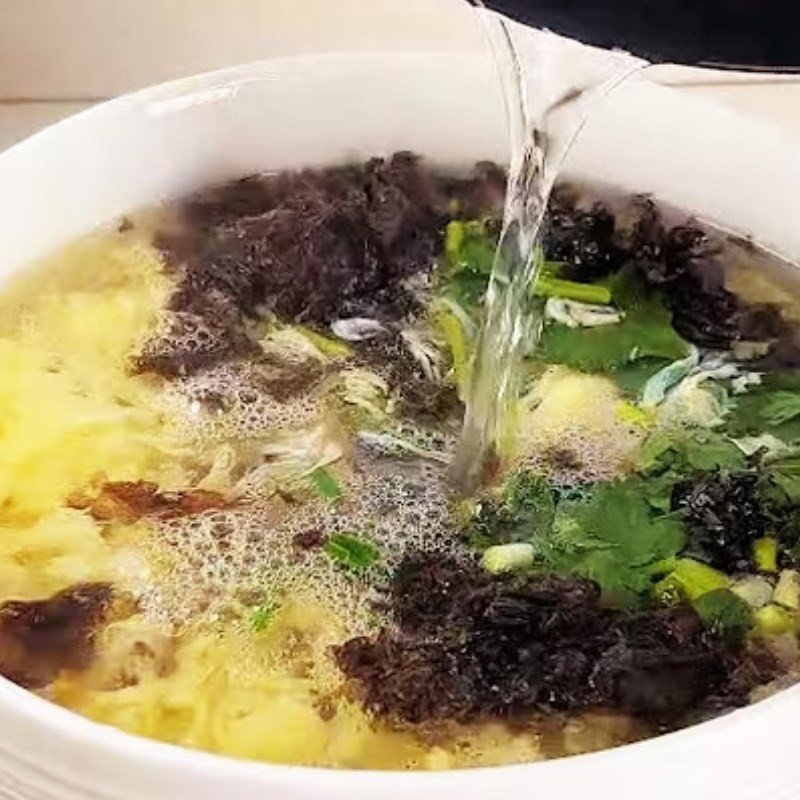 Đổ trứng đã đánh tan vào nồi nước đang xoáy để tạo vân mây cho canh rong biển trứng