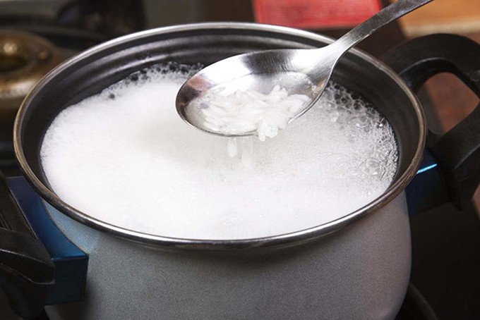 Gạo đang được cho vào nồi để nấu cơm bằng bếp gas