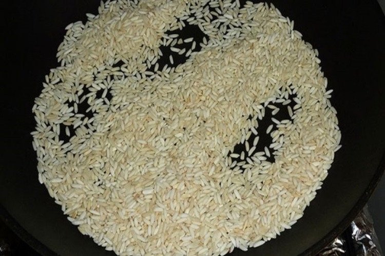 Gạo rang vàng thơm chuẩn bị nấu cháo cá lóc miền Tây