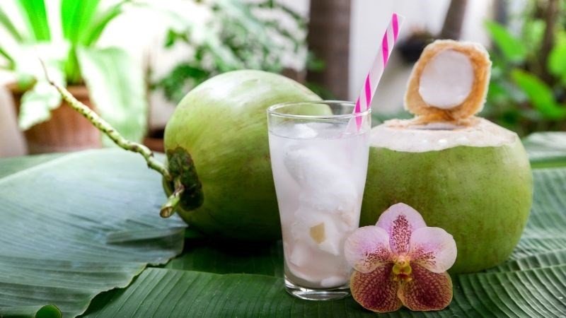 Hai ly nước dừa tươi đặt trên bàn với dừa cắt lát