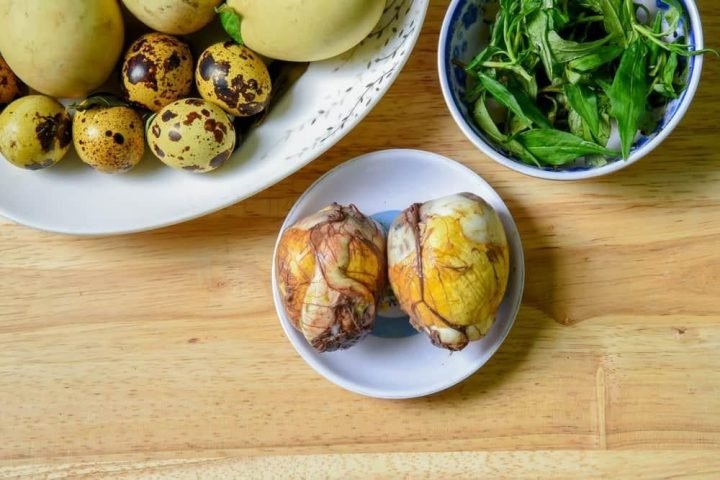 Hai quả trứng vịt lộn luộc thơm ngon cùng rau răm gừng ăn kèm, giúp cân bằng hương vị và dinh dưỡng.