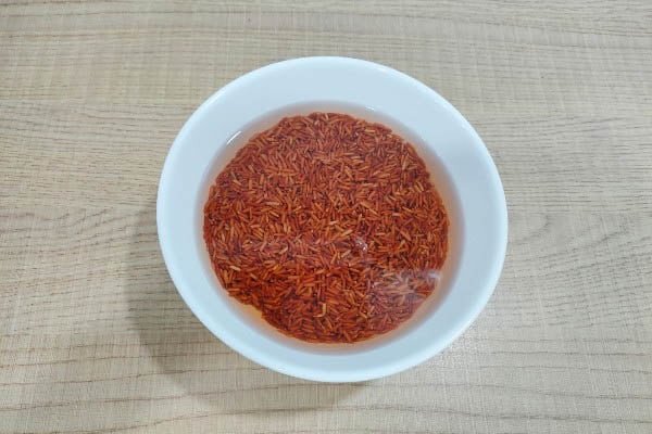 Cách Nấu Gạo Lứt Huyết Rồng Mềm Dẻo Chuẩn Vị Tại Nhà Hạt gạo lứt huyết rồng đang được ngâm trong nước để mềm hóa trước khi nấu