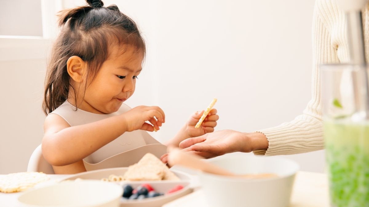 Hình ảnh một em bé đang ngồi ăn bánh Goute dưới sự giám sát của người lớn