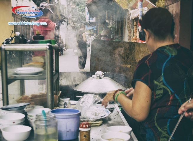 Hình ảnh người phụ nữ đang cẩn thận chọn lọc gạo để làm bột bánh cuốn tại nhà