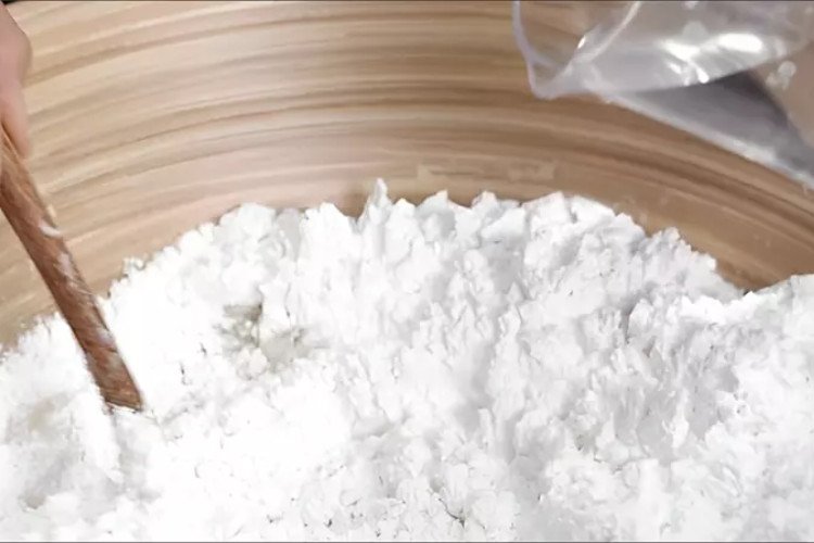 Hỗn hợp bột nếp và nước đường đang được trộn đều, tạo thành phần vỏ bánh in cơ bản, nơi chứa phần lớn lượng calo.