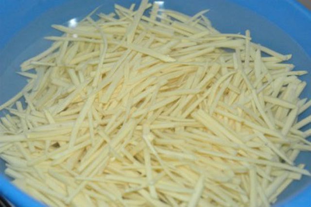 Khoai lang thái sợi mỏng đều đang được ngâm trong nước muối loãng để làm bánh rán