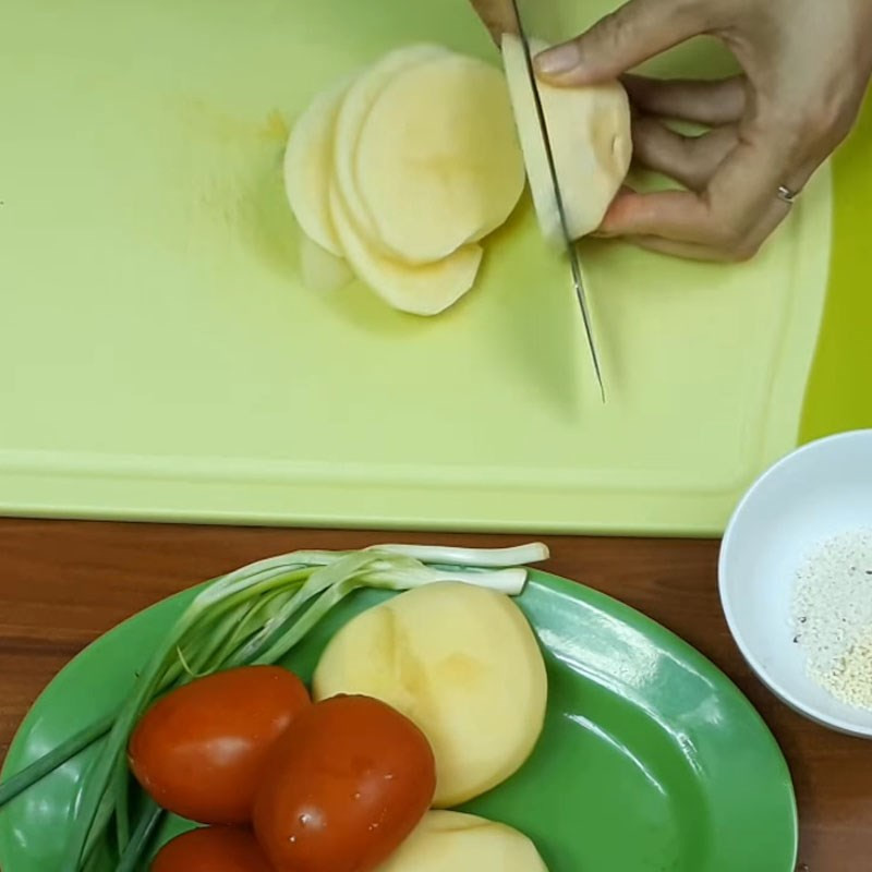 Khoai tây được gọt vỏ và thái lát mỏng chuẩn bị cho món cà chua xào
