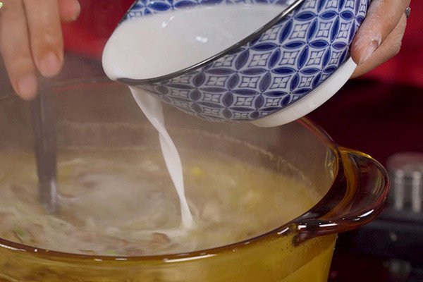 Kỹ thuật khuấy đều tay khi thêm bột năng vào súp bào ngư để đạt độ sánh mịn.