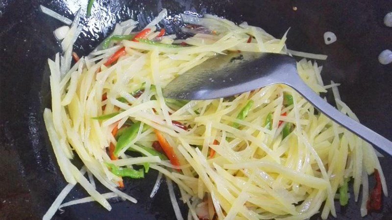 Kỹ thuật xào khoai tây trên chảo nóng, đảo nhanh tay để khoai chín đều và giòn