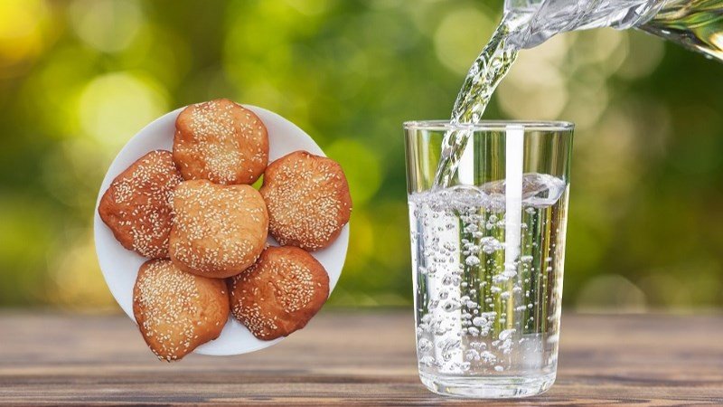 Ly nước lọc trong lành bên cạnh bánh tiêu, nhấn mạnh tầm quan trọng của việc uống đủ nước cho quá trình chuyển hóa.