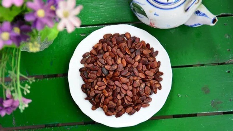Ly nước mát bên cạnh hạt dưa, hình ảnh gợi ý giải pháp cho vấn đề nóng trong người khi ăn hạt dưa.