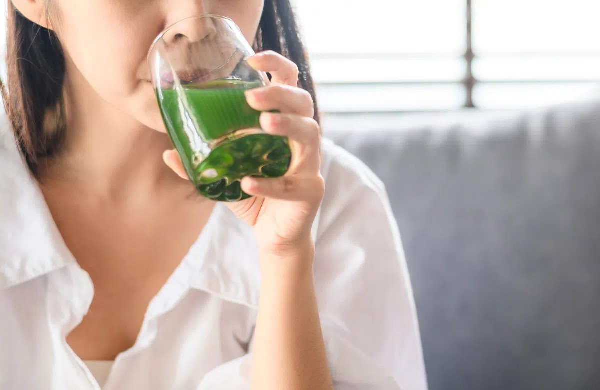 Ly nước rau diếp cá màu xanh tươi, đặt cạnh lá diếp cá tươi và chanh