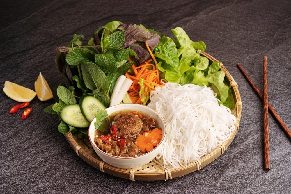 Mâm cơm gia đình với nhiều món ăn dinh dưỡng, bao gồm một bát bún hấp dẫn