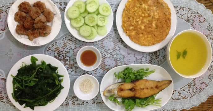 Mâm cơm với trứng chiên thịt, cá thu chiên, thịt viên chiên và rau mồng tơi luộc
