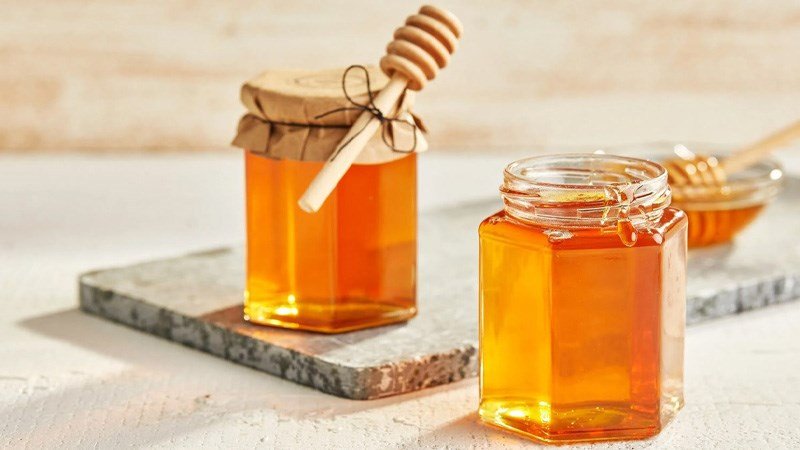 Mật ong vàng óng và hũ đựng, gợi ý phương pháp tự nhiên làm dịu cổ họng sau khi ăn hạt dưa.