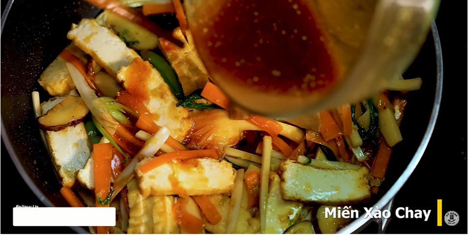 Miến và rau củ đang được xào đều trên chảo, tạo nên món miến xào chay hấp dẫn