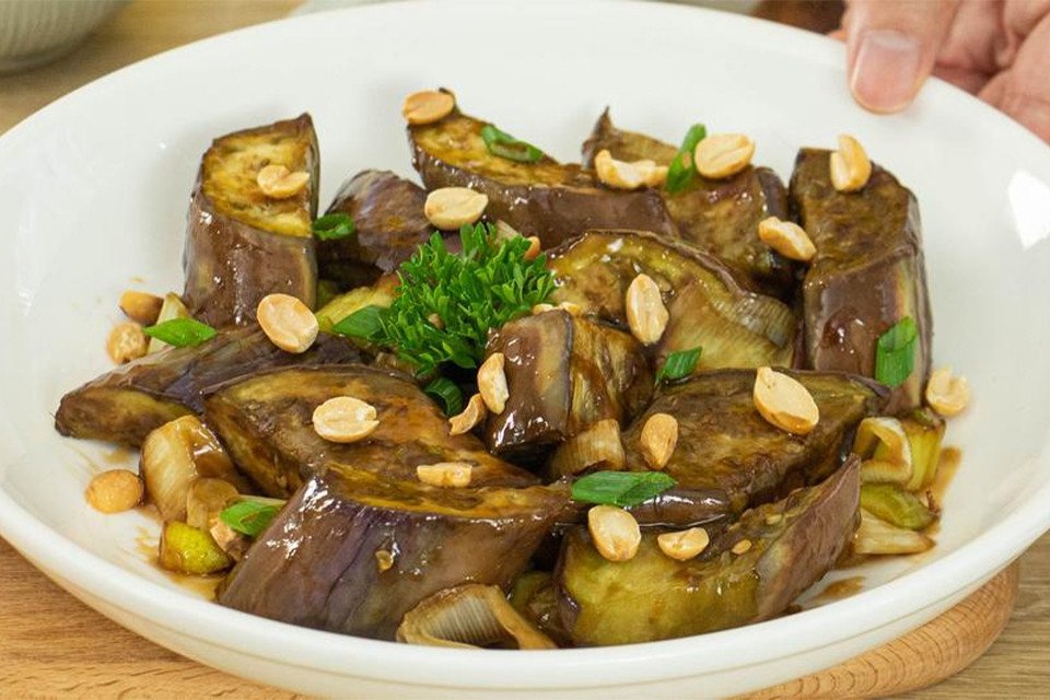 Món cà tím xào lá lốt đã hoàn thành, được bày ra đĩa với màu tím và xanh tươi của lá lốt, có thể rắc thêm ớt thái lát.