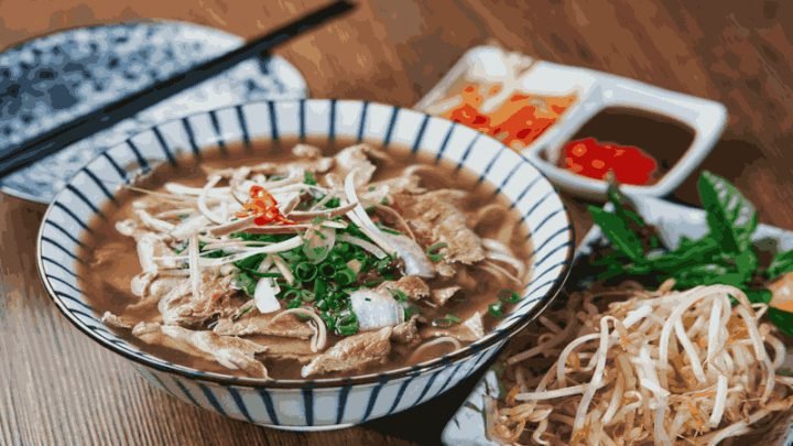 Món phở truyền thống Việt Nam với bánh phở, thịt và rau thơm