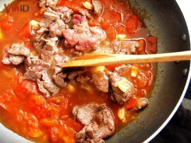 Món thịt heo đang được sốt cùng cà chua tươi trên chảo nóng
